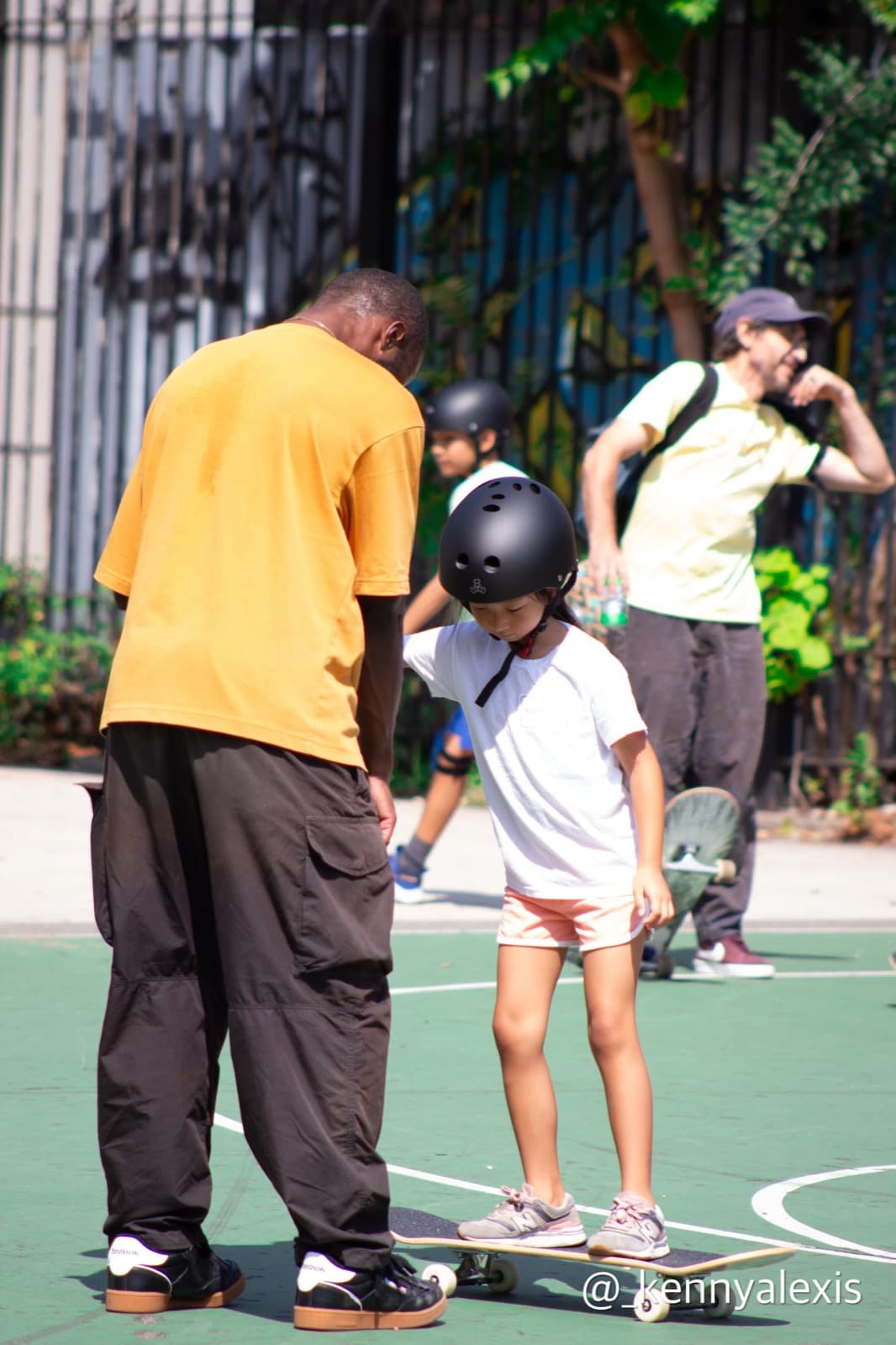 Leon Toppin teaching a young student to balance on a skateboard during a private lesson