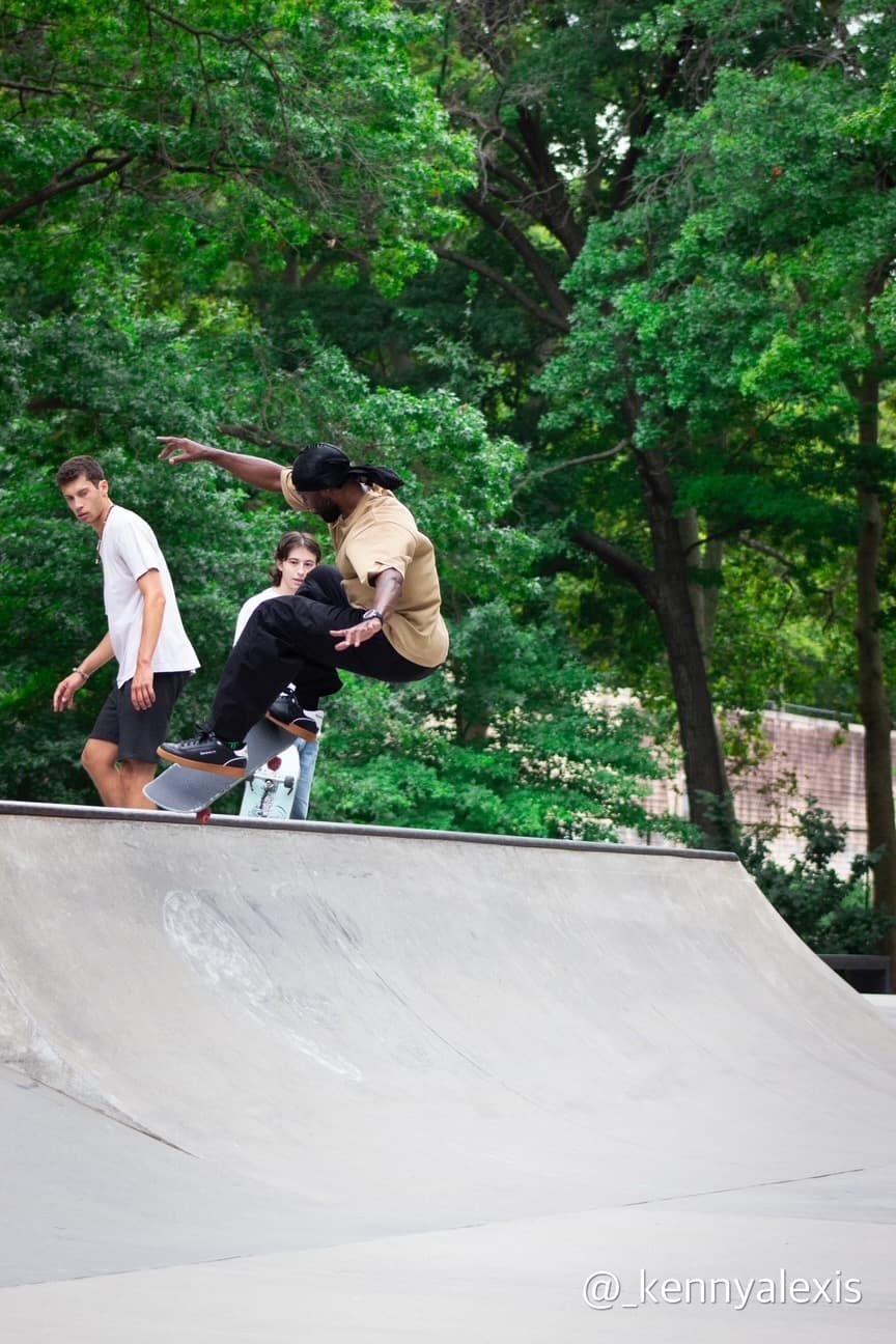 Leon Toppin dropping into a quarter pipe at a skatepark surrounded by trees
